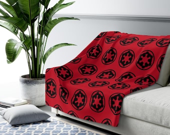 May include: A red fleece throw blanket with a repeating pattern of black Imperial insignia from Star Wars.