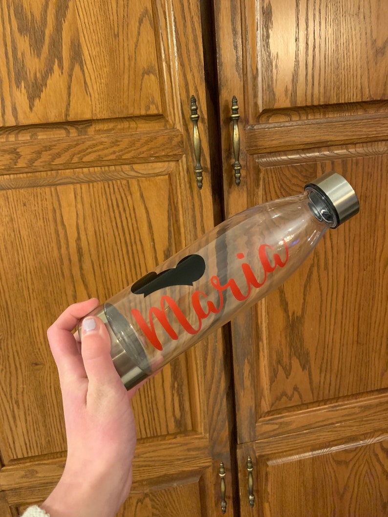 May include: A clear glass water bottle with a black heart and the name "Maria" written in red lettering.