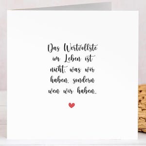 Könnte beinhalten: Eine weiße Grußkarte mit schwarzer Schrift: "Das Wertvollste im Leben ist nicht, was wir haben, sondern wen wir haben..." Ein kleines rotes Herz unten.