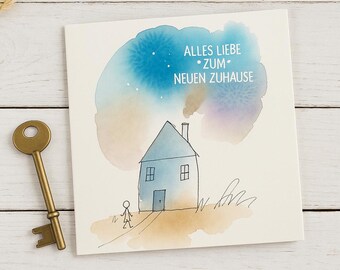 May include: A greeting card with a watercolor illustration of a blue house with smoke rising from the chimney, and the text "ALLES LIEBE ZUM NEUEN ZUHAUSE". A gold-colored key is next to the card.