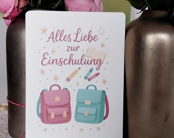May include: A greeting card with the text "Alles Liebe zur Einschulung" in pink script, featuring illustrations of two backpacks, pencils, crayons, and stars. The card is white with a soft, pastel color palette.