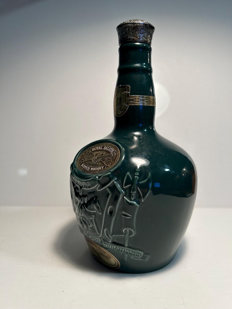 May include: A green ceramic bottle of Royal Salute Scotch Whisky. The bottle has a silver cap and a gold label with the words "Royal Salute" and "Scotch Whisky".