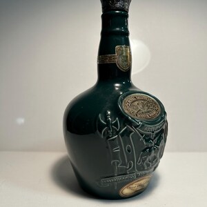 May include: A green glass bottle of Chivas Regal Scotch Whisky with a silver top and a label that says "Chivas Regal" and "Scotch Whisky".