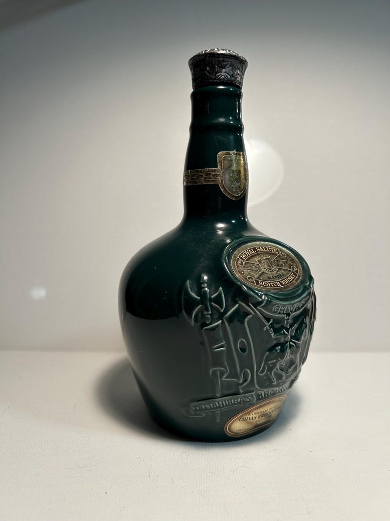 May include: A green glass bottle of Chivas Regal Scotch Whisky with a silver top and a label that says "Chivas Regal" and "Scotch Whisky".