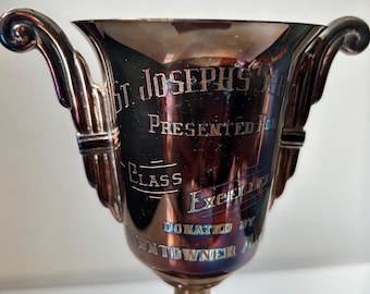May include: Silver trophy cup with engraved text: "St. Joseph's School Presented for Class Excellence Donated by Towner Mfg."