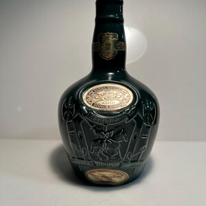 May include: A green glass bottle of Chivas Regal Royal Salute Scotch whisky with a gold label and a silver top.