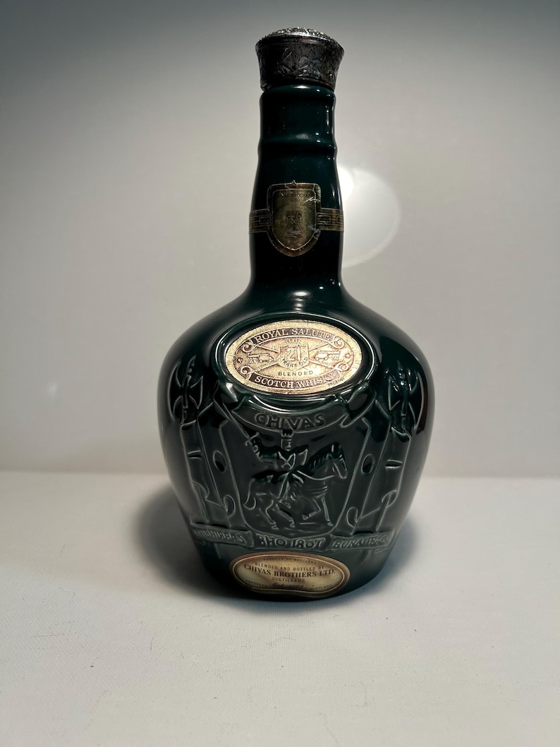 May include: A green glass bottle of Chivas Regal Royal Salute Scotch whisky with a gold label and a silver top.
