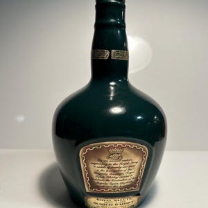 May include: A dark green glass bottle of Royal Salute Scotch Whisky. The bottle has a gold label with the text "Royal Salute Scotch Whisky" and "Chivas Brothers Ltd."