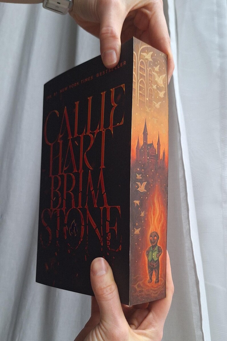 May include: A hardcover book titled "Callie Hart Brimstone" with red lettering on a black background. The spine features a castle illustration with a fiery figure. The book is a New York Times Bestseller.