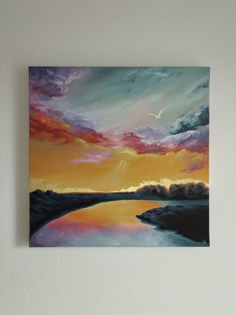 A painting on canvas of a colourful sky with pinks, purples, yellows and blues reflecting on a lake with gold foil along the horizon and a gold bird in the sky