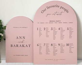 May include: Pink archway wedding signage with the text "Our favorite people, your seat awaits."  The sign also includes the text "Welcome to the wedding of Ann and Baraket" and "16 February 2024".  The sign also includes a seating chart with table numbers and guest names.