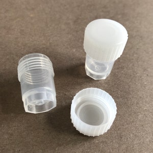 May include: Three clear plastic vials with white screw-on lids. The lids have a ridged design.