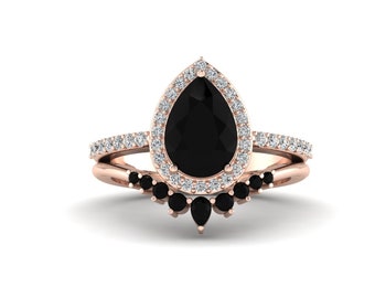 May include: A pear-shaped black diamond engagement ring with a halo of smaller diamonds set in rose gold. The ring is paired with a matching wedding band featuring a row of black diamonds.