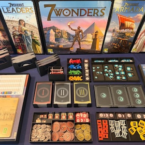 May include: A 7 Wonders board game set including the base game and expansions Cities, Leaders, Armada, and Edifice. The collection features game boxes, card decks labelled I, II, and III, various coloured plastic tokens, cardboard coins, and game boards.