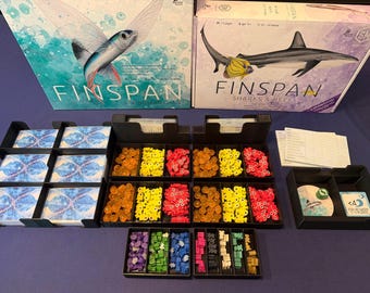 以下が含まれることがあります： 「Finspan」と「Finspan Sharks & Reefs」の2つのボードゲームボックスとゲームコンポーネント。 「Finspan」ボックスには翼のある魚が、一方「Sharks & Reefs」ボックスにはサメが描かれています。 コンポーネントには、カード、トークン、ゲームピースが含まれます。