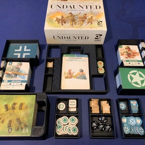 May include: The board game "Undaunted: Normandy" with its components arranged. The game includes cards, tokens, dice, and storage trays. The box art shows soldiers in a war setting. The game's components are neatly organized in black trays.