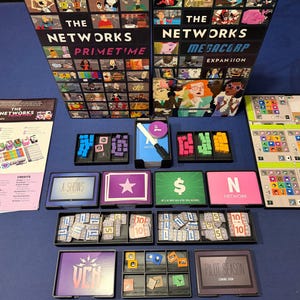 May include: The Networks Primetime and Megacorp board game set includes two large game boxes, a rulebook, multiple player boards, black plastic component trays, various colored wooden cubes, cardboard tokens, and card decks featuring text like A Shows, Pilot Season, and Network.