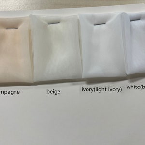 May include: Four fabric swatches in different shades of white: champagne, beige, ivory (light ivory), and white (blueish).