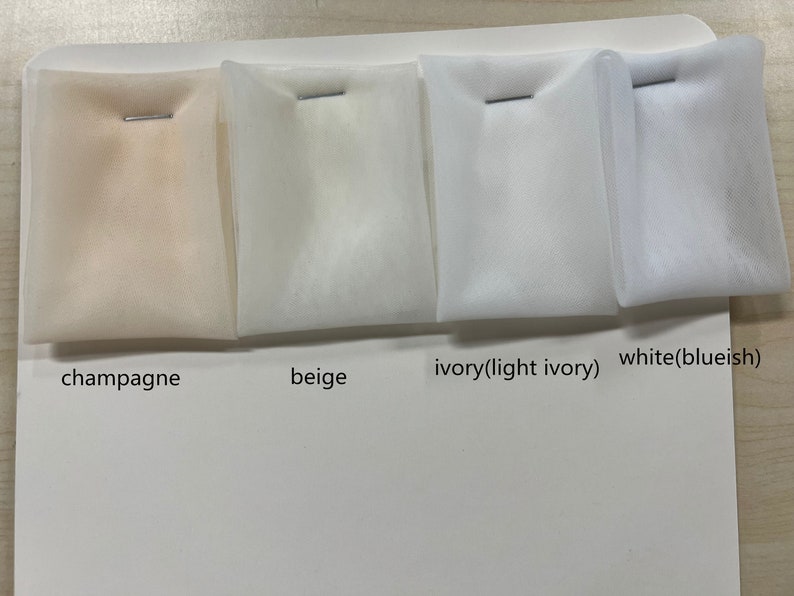 May include: Four fabric swatches in different shades of white: champagne, beige, ivory (light ivory), and white (blueish).