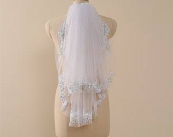 May include: A white bridal veil with a beaded lace trim. The veil is displayed on a mannequin.