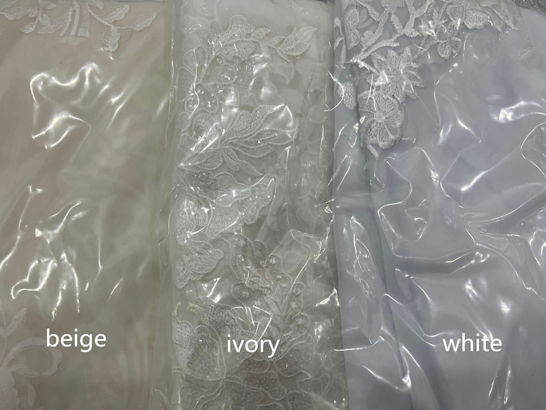 May include: Three swatches of fabric in beige, ivory, and white. Each swatch has a floral lace pattern.