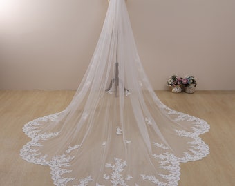 May include: A white bridal veil with a scalloped lace trim and delicate floral embroidery. The veil is made of soft tulle and is long enough to flow behind the bride as she walks down the aisle.