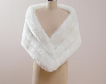 May include: White faux fur shawl draped over a dress form. The shawl is soft and fluffy, and it would be a great addition to any winter outfit.