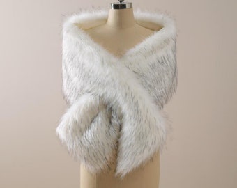 May include: White faux fur shawl with a soft, fluffy texture. The shawl is draped over a mannequin and is ideal for adding a touch of elegance to any outfit.