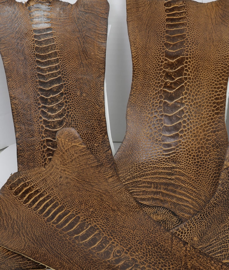 May include: Two pieces of brown ostrich leather with a textured pattern. The leather is soft and supple, and it has a natural, rustic look.