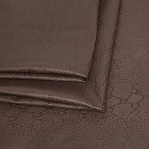 May include: Close-up of brown faux leather fabric with a snakeskin pattern.
