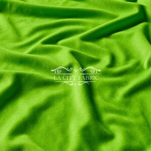 May include: A bright green fabric with a smooth texture. The fabric is folded and draped, showing its soft and flowing nature.
