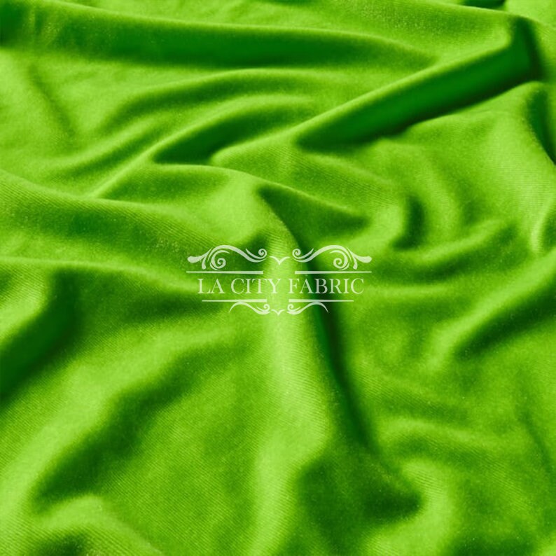 May include: A close-up of a bright green fabric with a soft, smooth texture. The fabric is draped and folded, creating a sense of movement and flow. The fabric is perfect for sewing projects, crafts, and home decor.