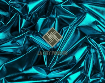 May include: Close-up of a teal fabric with a metallic sheen. The fabric is heavily creased, creating shadows and highlights. The logo "LA CITY FABRICS" is visible in the bottom right corner.
