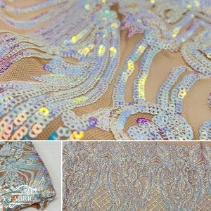 Op de afbeelding: Iridescent witte pailletten op een transparante mesh stof met een bloemenpatroon. De pailletten zijn in een golfpatroon gerangschikt. De stof is beige van kleur.
