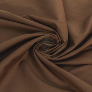 May include: A solid dark brown fabric with a smooth, matte texture. The material is gathered in the center, creating deep, flowing folds and soft shadows that highlight the consistent, rich brown color across the entire surface of the textile.