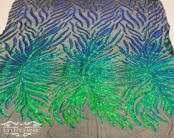May include: Green and blue iridescent sequins on a black mesh fabric. The sequins are arranged in a swirling pattern, creating a dynamic and eye-catching design.