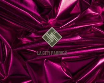 May include: A close-up of a shiny, magenta fabric with a metallic sheen. The fabric is heavily wrinkled, creating shadows and highlights. The words "LA CITY FABRICS" are visible in white text.