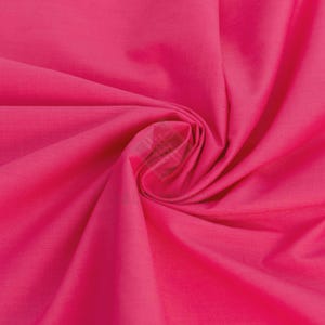 Peut inclure: Un tissu rose vif vibrant présentant une texture lisse et mate. Le matériau est rassemblé en un tourbillon central, créant des plis profonds et rayonnants ainsi que des ombres qui soulignent la couleur unie et constante sur toute la surface.