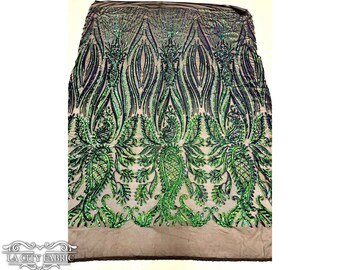 May include: Green and blue sequined fabric with a paisley pattern. The fabric is on a beige background.