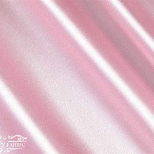 May include: A close-up of a smooth, pink satin fabric with a subtle sheen. The fabric is draped in soft folds, creating a luxurious and elegant look.