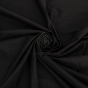 May include: A solid black fabric with a smooth, matte texture, arranged in a swirling, draped pattern. A faint, semi-transparent watermark logo featuring the text LA CITY FABRICS is visible in the center of the fabric folds.
