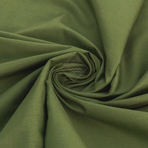 Puede incluir: Una tela de color verde oliva sólido con una textura suave y mate. El material está recogido en el centro, creando pliegues suaves y fluidos con sombras profundas que resaltan el tono terroso y uniforme del tejido en toda su superficie.