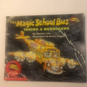 Op de afbeelding: De omslag van het boek The Magic School Bus toont een gele schoolbus die door een donkere, stormachtige lucht vliegt met de tekst "The Magic School Bus Inside a Hurricane" en "By Joanna Cole Illustrated by Bruce Degen".
