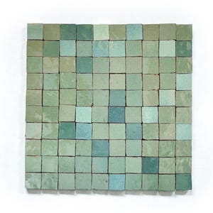 Könnte beinhalten: Ein quadratisches Mosaikfliesen-Design, das aus kleinen, quadratischen Fliesen in verschiedenen Grün- und Blautönen besteht. Die Fliesen sind in einem Raster angeordnet und erzeugen eine strukturierte Oberfläche. Der Gesamteffekt ist eine Mischung aus kühlen, erdigen Tönen.