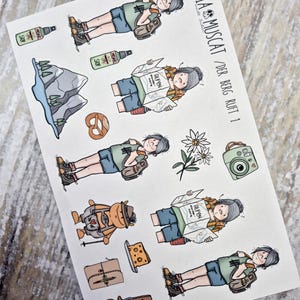 Könnte beinhalten: Ein Stickerbogen mit dem Titel CLAUDIA MUSCAT / DER BERG RUFT 1 mit Cartoon-Illustrationen von Wanderern, Bergen, einer Brezel, Kamera, Blume, Käse, Notizbuch und Kuhglocke. Die Wanderer tragen grüne T-Shirts, blaue Shorts und Rucksäcke.
