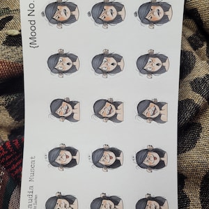 May include: A sheet of stickers featuring a cartoon character with different facial expressions. The character has black hair, brown eyes, and a pink nose. The stickers are labeled "Mood No. 2".