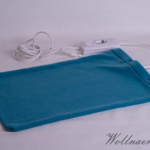 Könnte beinhalten: Ein blaues Heizkissen aus Fleece mit einem weißen Kabel und einem weißen Schalter. Das Heizkissen liegt auf einer weißen Oberfläche.