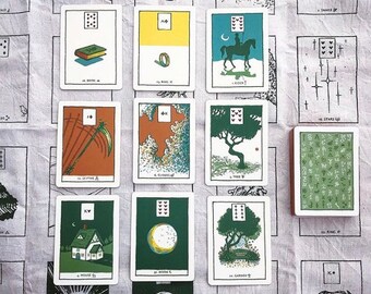 Può includere: Un mazzo di carte dei tarocchi con illustrazioni di vari simboli e scene. Le carte sono disposte in uno spread su un tessuto a motivi bianchi e verdi. Le carte includono il 10 di Spade, l'8 di Nuvole, il 5 di Albero, il 10 di Luna, il 10 di Giardino, il 10 di Libro, l'8 di Anello, l'1 di Cavaliere, il 16 di Stelle, il 10 di Re, il 10 di Falce e il 10 di Casa.