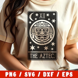 Op de afbeelding: Een beige T-shirt met een zwart-witte afbeelding van een tarotkaart. De kaart toont een gestileerd gezicht met een halve maan en sterren. De tekst "THE AZTEC." is onder de afbeelding gedrukt.