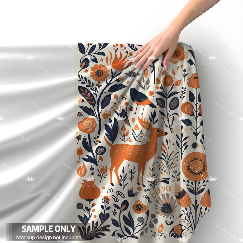 K&ouml;nnte beinhalten: Ein wei&szlig;er Stoff mit einem bunten Blumenmuster mit einem Reh, V&ouml;geln und Blumen. Der Stoff ist umgeklappt und wird von einer Hand gehalten.